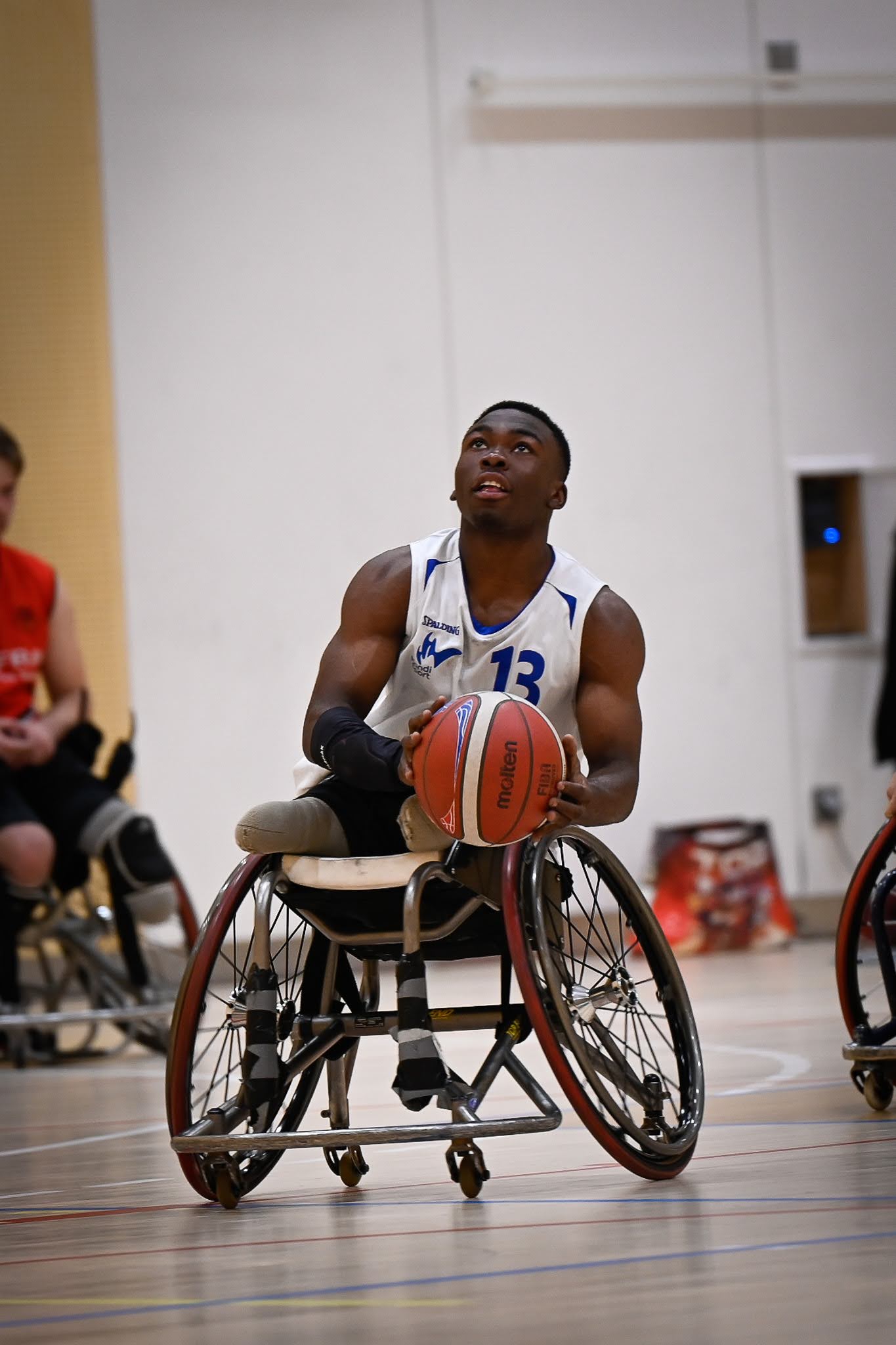 cette photo illustre un jeune double amputé en train de faire du basket fauteuil