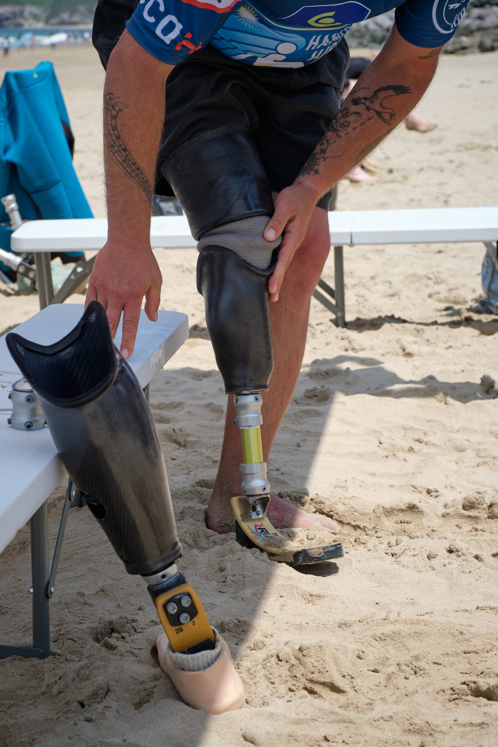 une personne amputée changeant de prothèses pour faire du surf avec un appareillage adapté